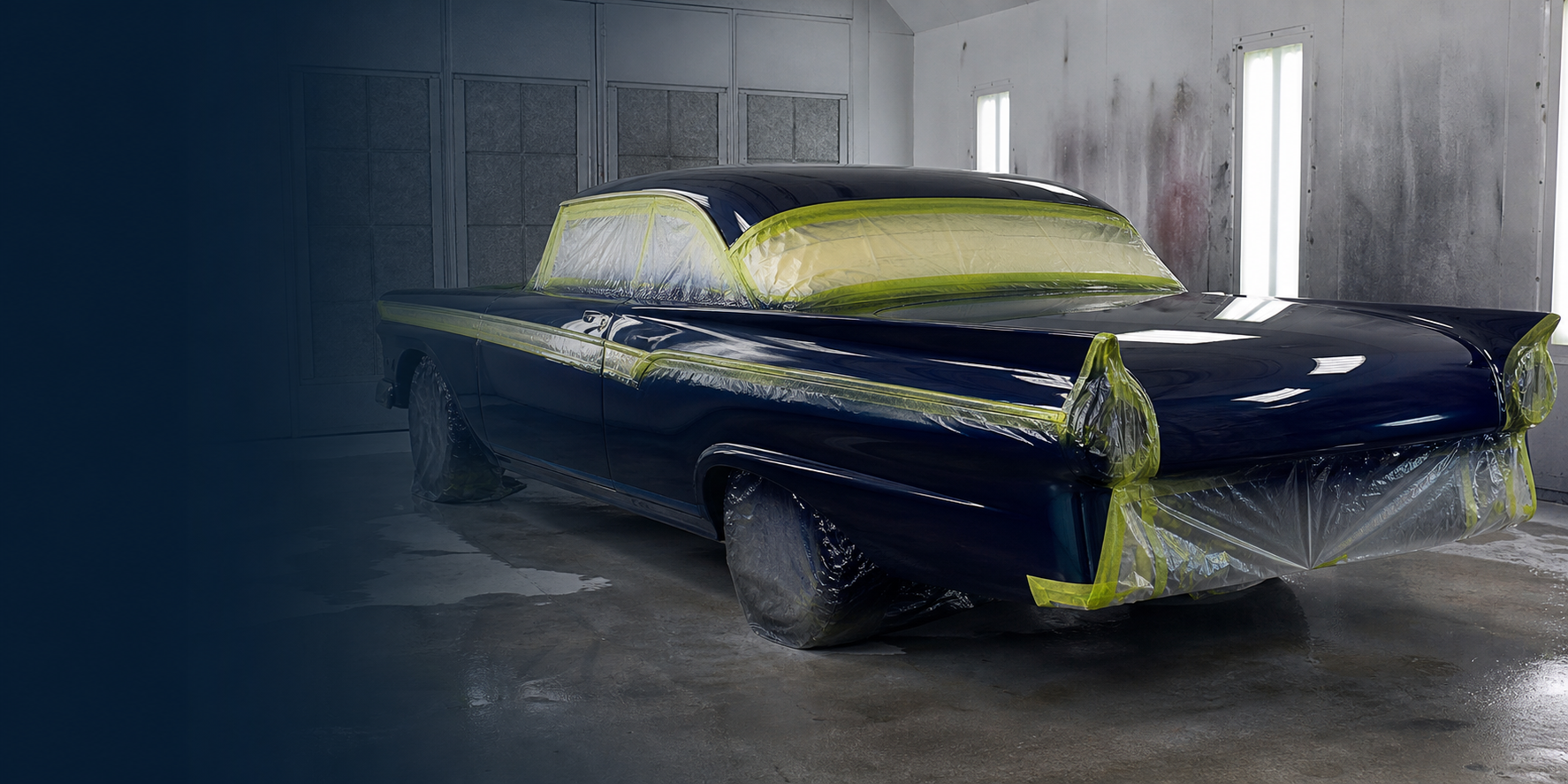 Deep navy classic car freshly painted in a booth with masked windows and trim